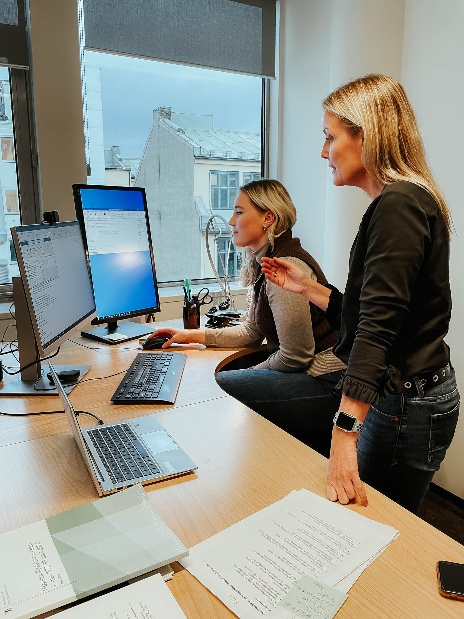 Selma Vedum Håland og Helle Campbell ser på en pc skjerm. Selma sitter og Helle gir instruks. Foto.