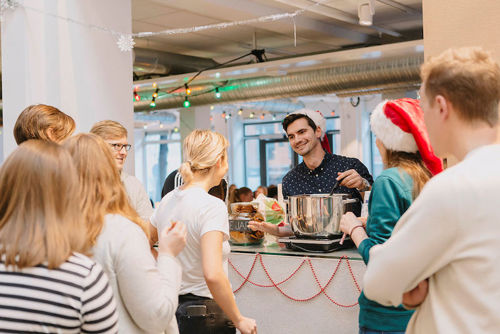 En ung mann serverer gløgg og peppekaker til studenter. 