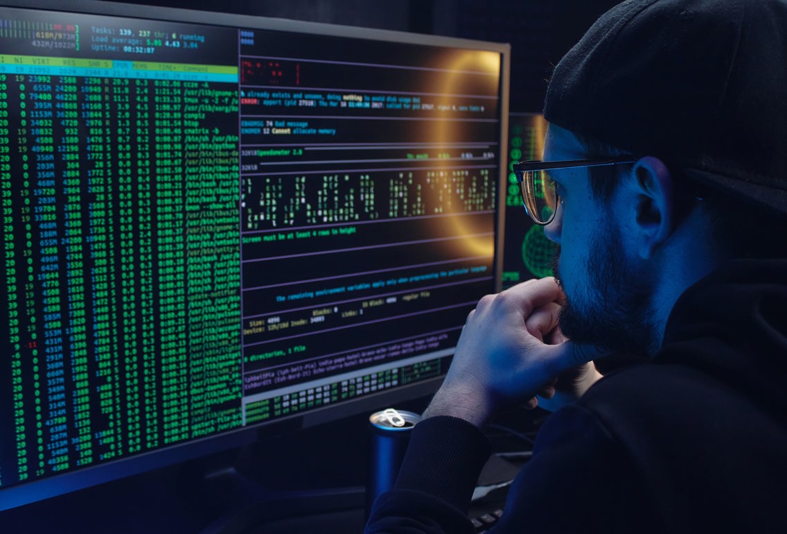 Young man with glasses looking at code on a computer screen