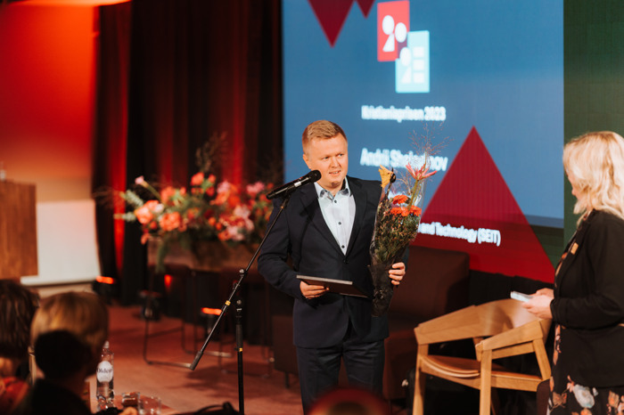 Andrii Shalaginov holder blomster og snakker i en mikrofon.