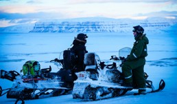 To menn med snøskutere i vinterlandskap