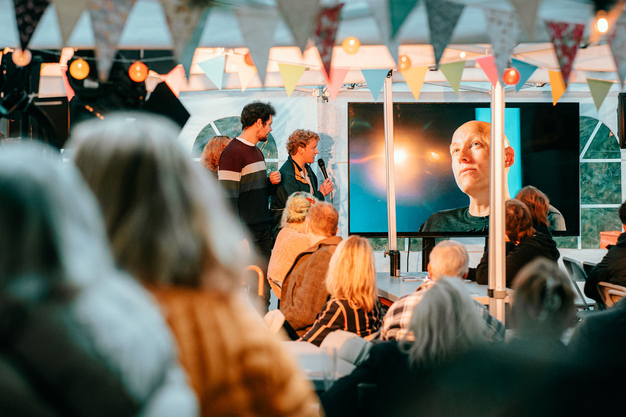 Studenter som presenterer et prosjekt for publikum inne i et telt på Elgsletta i Oslo. 