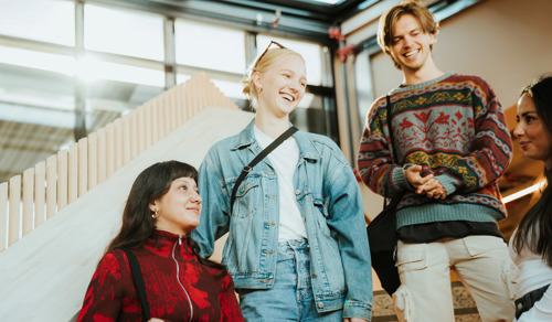 Smilende studenter på vei ned trappen etter forelesning