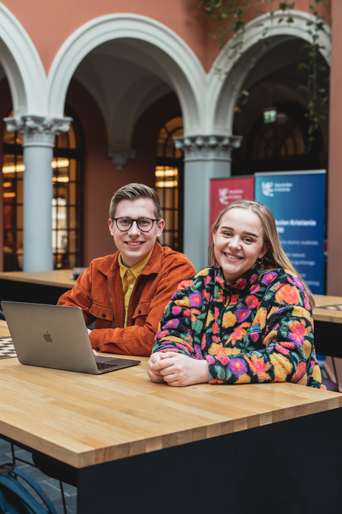 To studenter fra tekst og skribent smiler mot kamera.