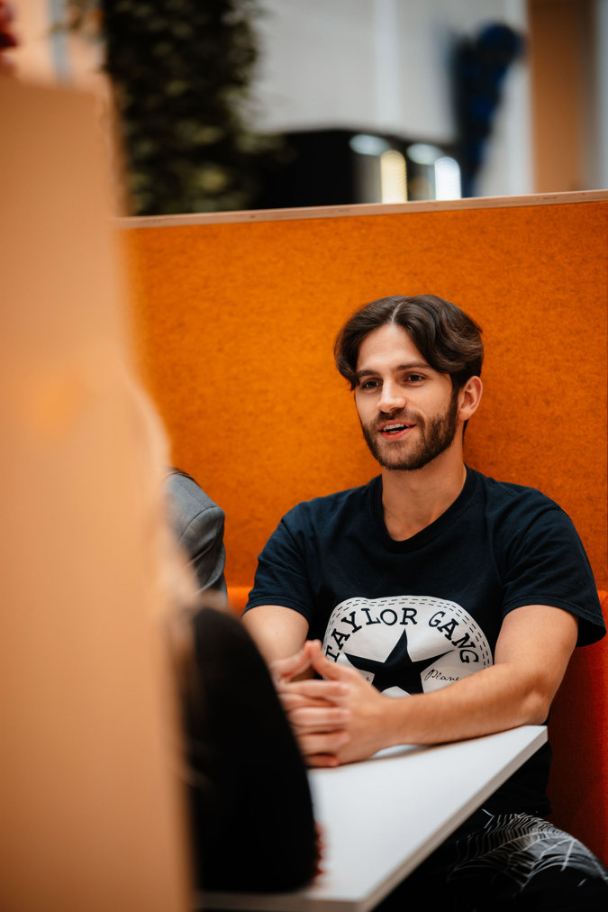 En student sitter ved et bord med foldede hender.