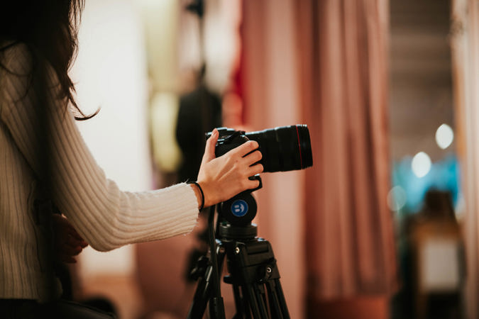 En person holder i et kamera som står på et stativ