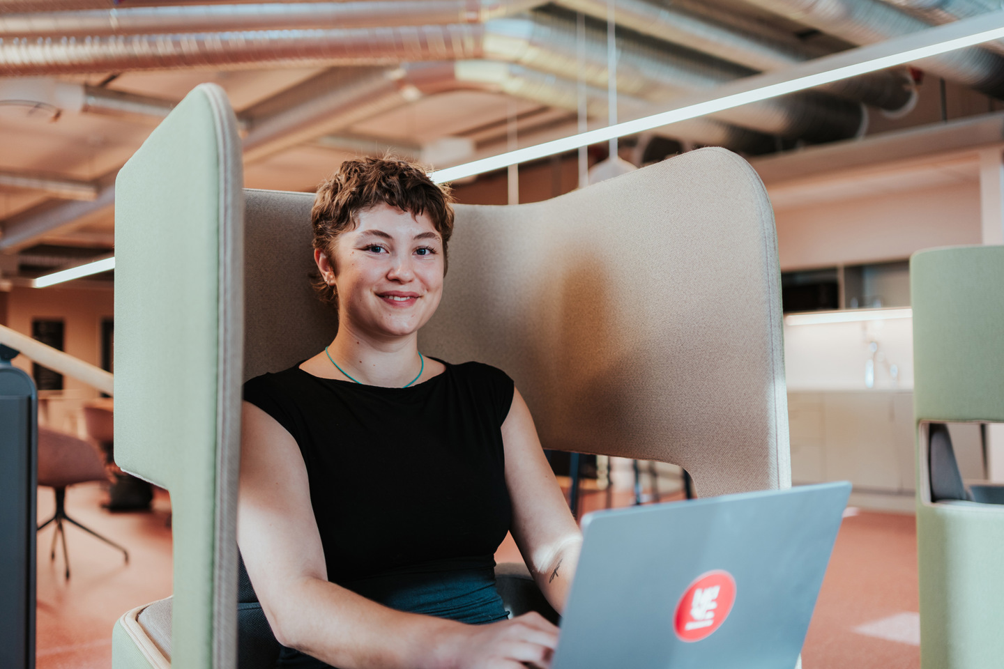 Student med PC sitter i en stol og jobber.