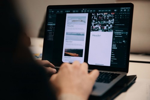 Bilde av laptop-skjerm med hender som jobber på tastaturet.