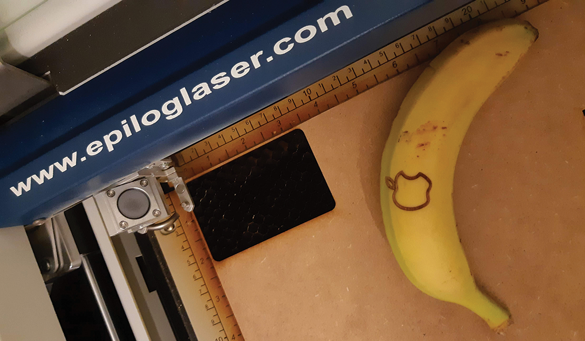 Laserskjærer som har laget et eple-merke på en banan