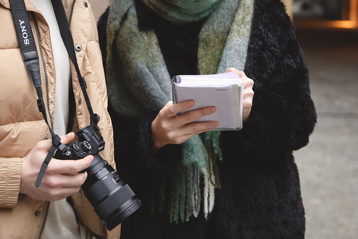 Illustrasjonsfoto av to mennesker som holder skriveblokk og fotoapparat.