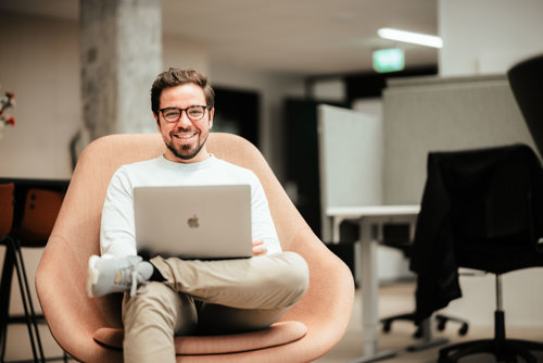 Mann med PC sitter i stol på kontor