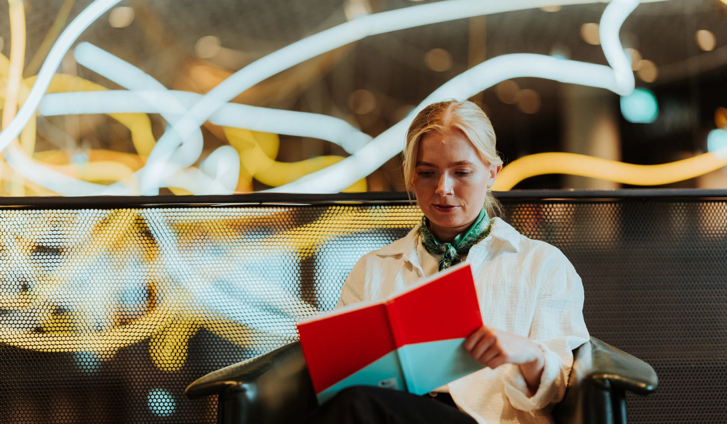 Kvinnelig nettstudent leser pensum på biblioteket