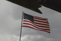 Det amerikanske flagg på en flaggstang med grå og mørk himmel i bakgrunnen