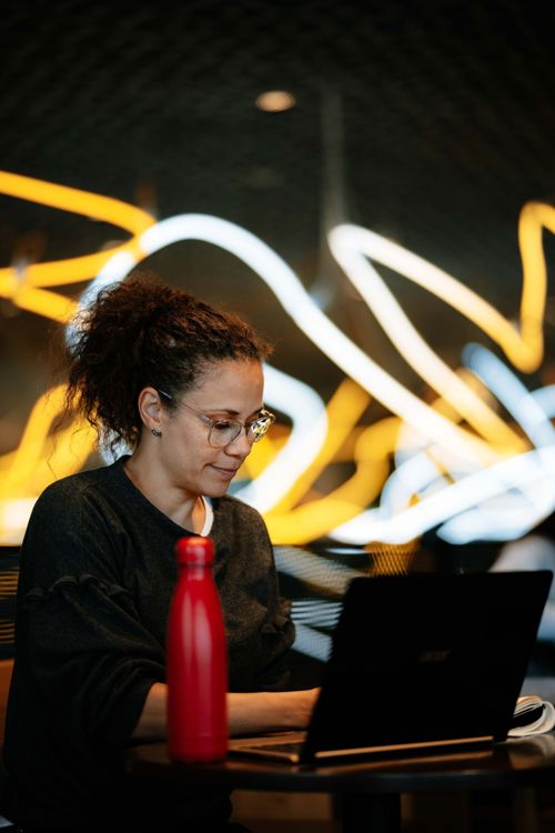 Kvinne sitter dypt fokusert med nettstudiene sine på biblioteket