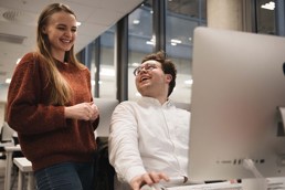 To studenter som står foran en Mac på Fagskolen Kristiania