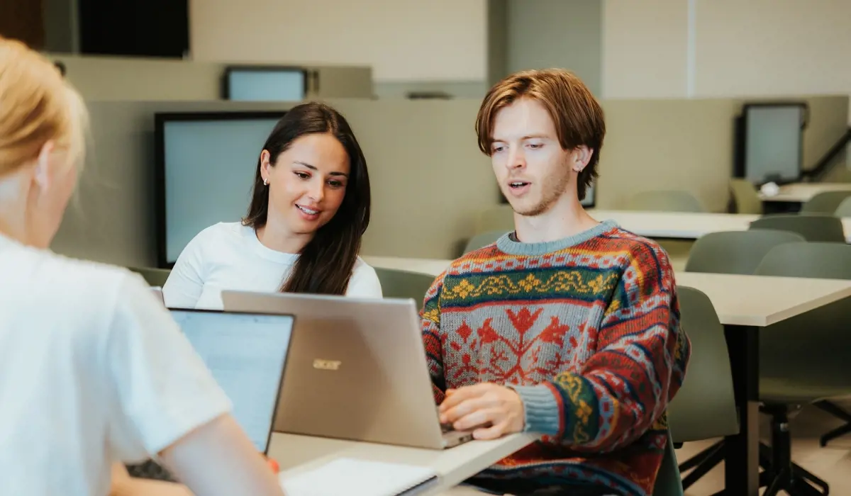 Tre studenter sitter med hver sin PC.