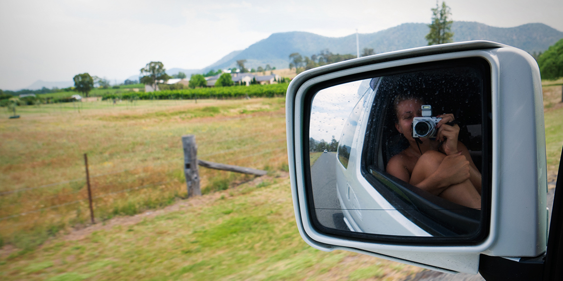 Mathilde i speilbildet på sidespeilet på bilen hun sitter i. 