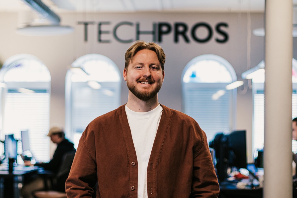 Bilde av Fredrik foran TECHPROSlogoen