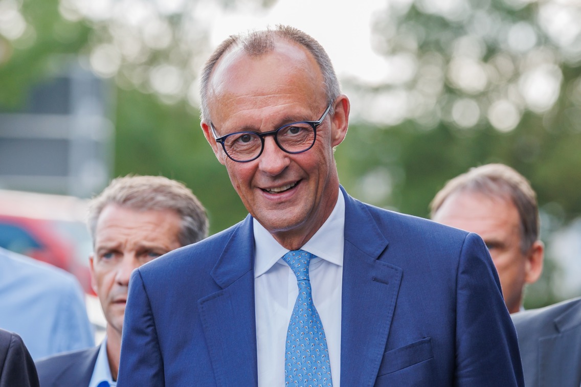 Friedrich Merz walking and smiling into the cameria.