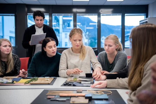 Foto av fem studenter som samarbeider rundt et bord.