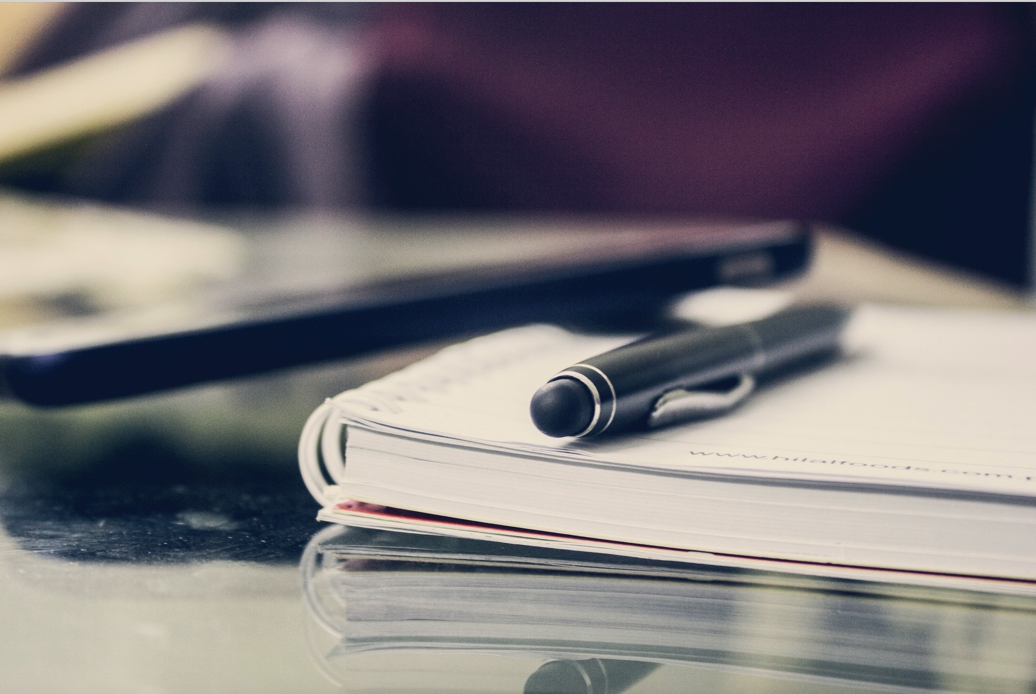 A pen lies on top of a notebook. Photo.