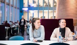 Foto av to kvinnelige studenter i en kantine.