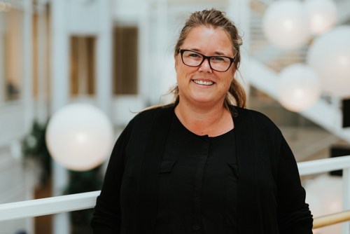 Portrett av kvinne med briller og håret satt opp i hestehale