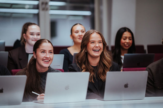 Studenter som smiler og følger med i forelesning