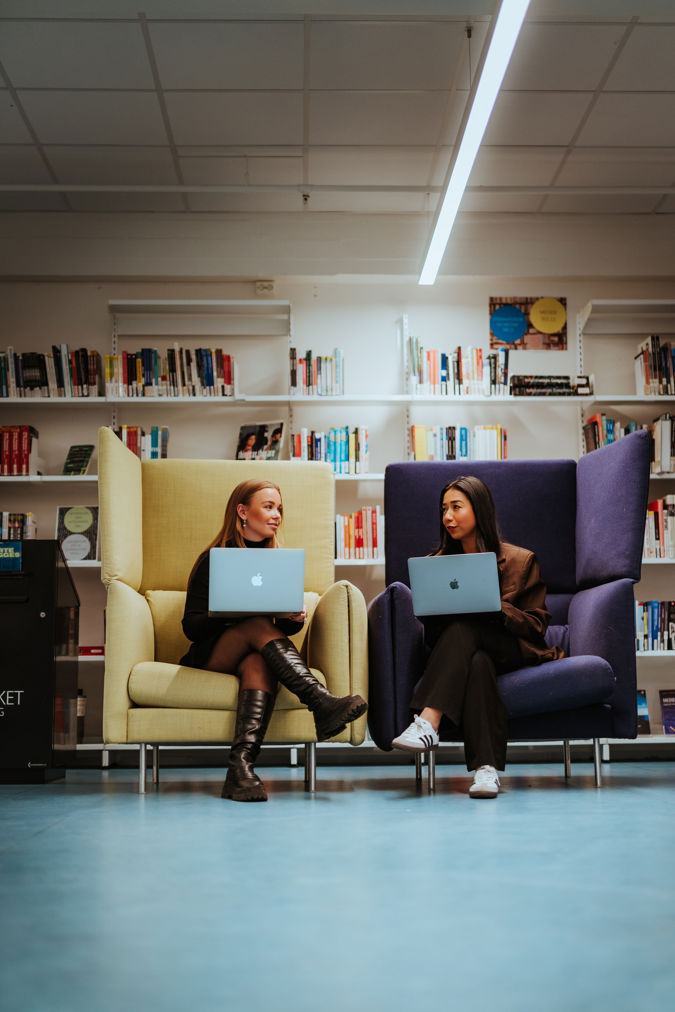 To studenter jobber på laptop i biblioteket